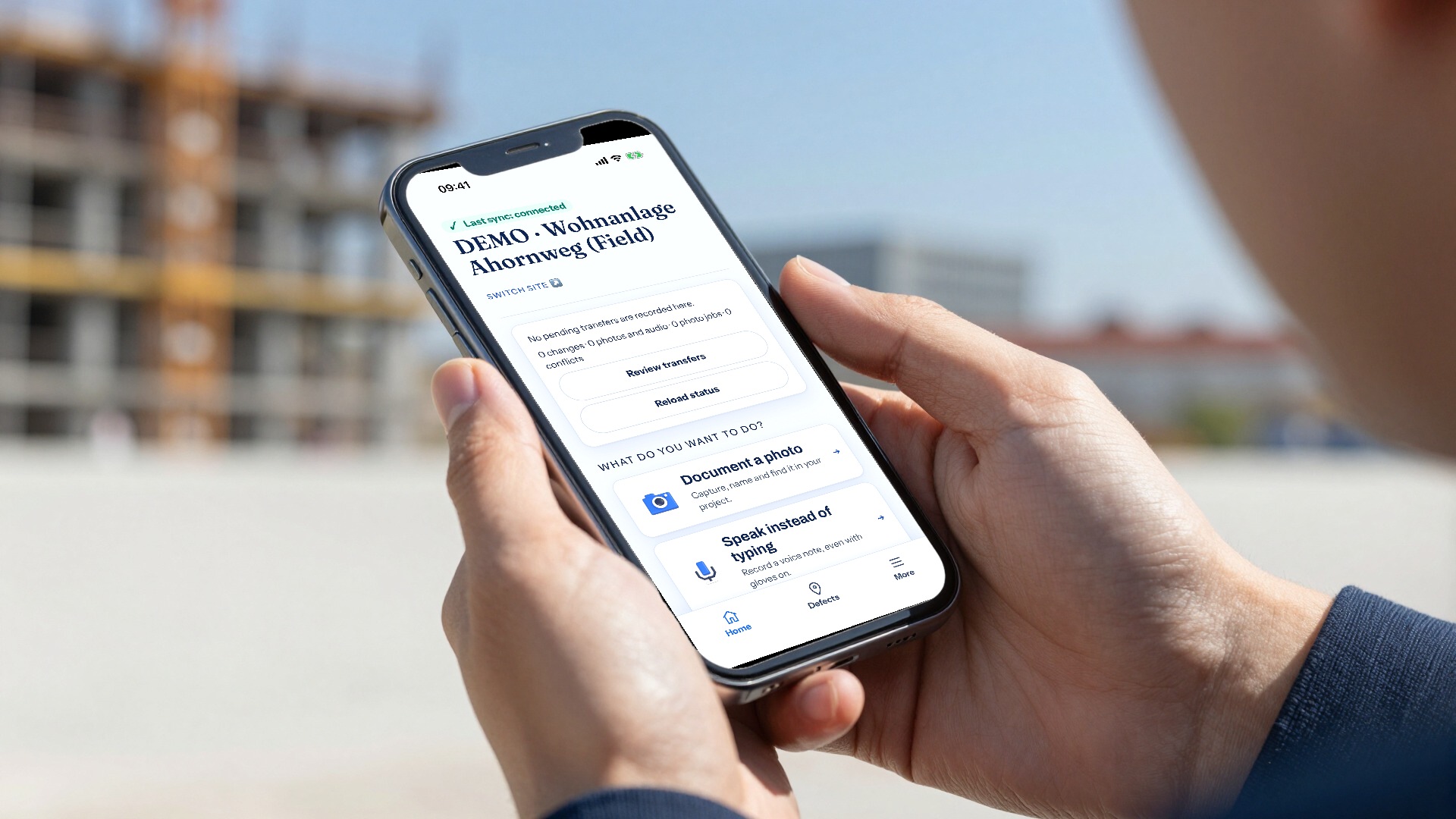 Hands holding a smartphone on a construction site, showing the Gewerkton app's home screen with a demo project